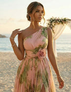 Woman in a pink floral dress standing on a beach with a sunset background