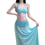A woman modeling a light blue two-piece swimwear set with a halter bikini top and a matching flowing sarong skirt, both accented with gold starfish-shaped details.