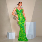 Woman in a green sequin dress standing against a beige background