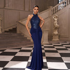 Woman in a blue evening gown standing in an elegant interior setting.
