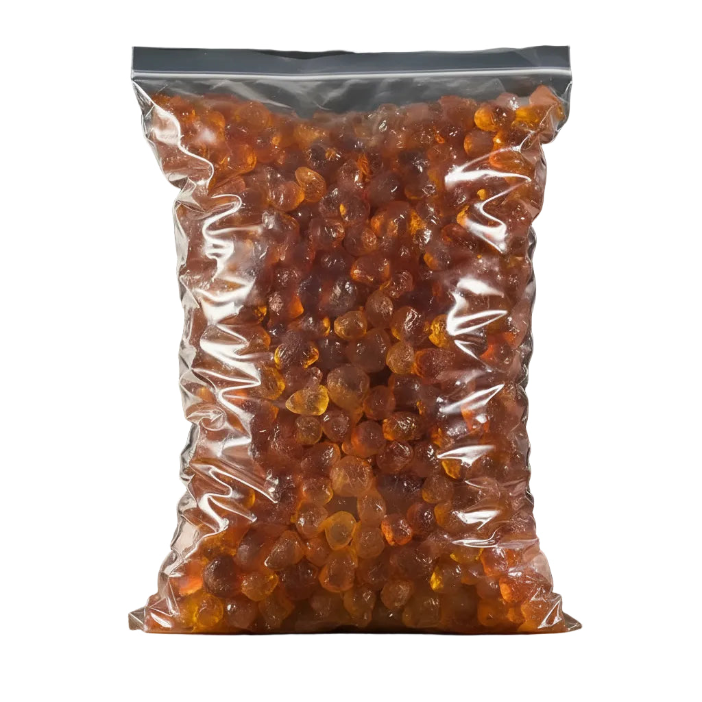 Clear bag of amber-colored gummy bears with a wooden spoon and bowl on a dark background