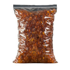 Clear bag of amber-colored gummy bears with a wooden spoon and bowl on a dark background