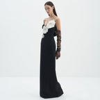 Black evening gown with white floral embellishments and black gloves on a white background