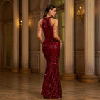 Woman in a burgundy sequin gown standing in an elegant interior setting.