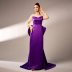 Woman wearing a purple evening gown with a beige top against a neutral background