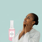 Woman applying rose water to her face with a bottle of Envidia Rose Water in the foreground.