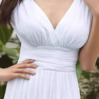 White dress with a V-neckline worn by a person, blurred green background