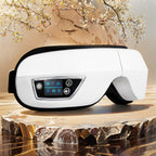 White eye massager with digital display on a wooden surface with decorative elements