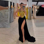 Woman in a gold top and black skirt with high slit standing in a dress shop.