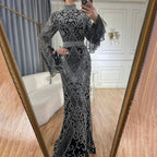 Person wearing a silver and black patterned dress in a room with a mirror.