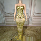 Mannequin wearing a gold evening gown with a textured skirt in an elegant room.