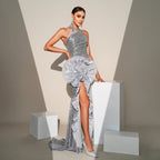 Woman in a silver evening gown with a large floral clutch against a neutral background