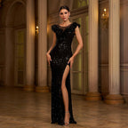 Woman in a black sequin evening gown standing in an elegant interior setting.