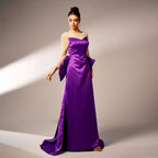 Woman wearing a long purple evening gown with a beige top against a neutral background