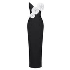 A black one-shoulder midi dress featuring three large white fabric flowers with rhinestone centers on the bodice, shown against a plain white background.