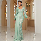Woman in a light green evening gown standing in an elegant hallway.
