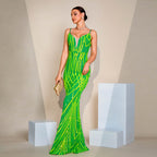 Woman in a green and yellow patterned evening gown standing against a neutral background