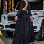 Person in a black dress standing in front of a white SUV with festive lights in the background