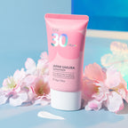 A pink tube of Japan Sakura Sunscreen SPF30 surrounded by cherry blossom flowers.