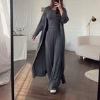 Person wearing a long gray dress in a room with a white sofa and lamp.