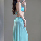 A woman wearing a light blue two-piece swimsuit with a halter-style bikini top and a matching long flowing skirt, photographed against a plain gray studio background.
