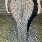 Mannequin wearing a beaded and sequined evening gown on a patterned carpet.