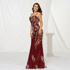 Woman wearing a burgundy floral evening gown against a white curtain backdrop