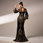 Woman wearing a black and gold evening gown with intricate designs on a neutral background