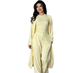 A woman modeling a light yellow two-piece loungewear set consisting of a fitted long-sleeve top and matching wide-leg drawstring pants, with a matching long open-front cardigan draped over her shoulders, set against a plain white background.