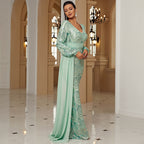 Woman in a light green evening gown standing in an elegant hallway.