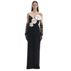 Black evening gown with white floral embellishments and black gloves on a white background