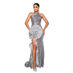 Woman in a silver evening gown with a large floral detail on a neutral background