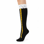 Black knee-high socks with yellow stripes and white tops on a beige background