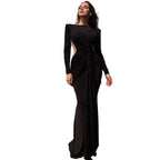 Woman in a black evening gown on a rooftop with cityscape in the background