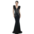 Black evening gown with floral embellishments on a mannequin against a white background