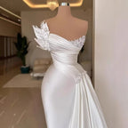 White evening gown with floral embellishments on a mannequin in an indoor setting.