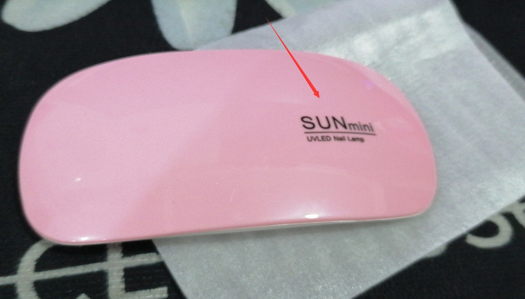 Pink UV/LED nail lamp with 'SUN mini' branding on a black and white patterned surface.