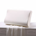 An ergonomic white slow rebound memory foam cervical spine space pillow resting on a bed