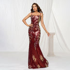 Woman wearing a red floral evening gown against a white curtain background