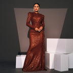 Woman in a brown sequined gown standing on white cubes against a gray background