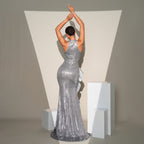 Woman in a silver sequin gown standing against a neutral background