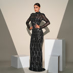 Woman in a black beaded evening gown standing against a neutral background
