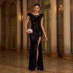 Woman in a black sequin evening gown standing in an elegant interior setting.