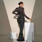 Woman in a black beaded evening gown standing against a neutral background