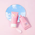 Two pink sunscreen bottles with a mirror reflecting a blue sky and clouds on a pink background.