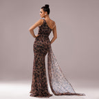 Woman wearing a leopard print evening gown with a sheer overlay on a neutral background
