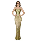 Mannequin wearing a gold evening gown with intricate design in an elegant room.