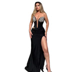 Woman in a black evening gown with silver embellishments standing in an elegant interior setting.