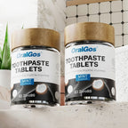 Two bottles of OralGos toothpaste tablets on a bathroom counter with text about cleansing.