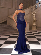 Woman in a blue evening gown standing in an elegant interior setting with stairs and classical architecture.